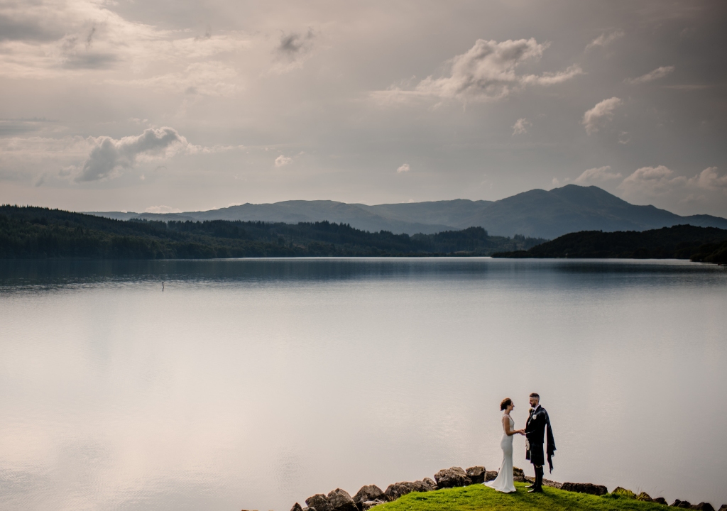 Couple standing on the banks of the loch in wedding attire