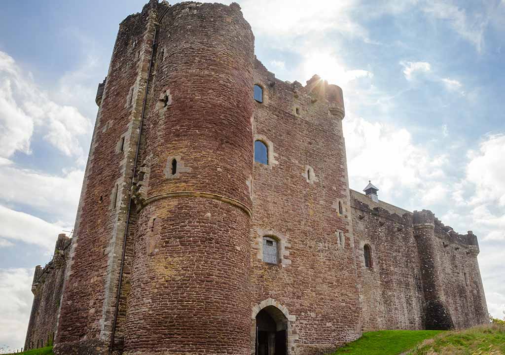 Doune Castle with a bright sky behind it.