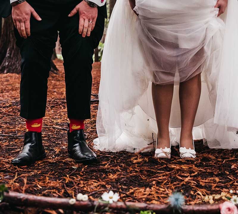 A bride and groom raise their trousers and dress to show funky socks.