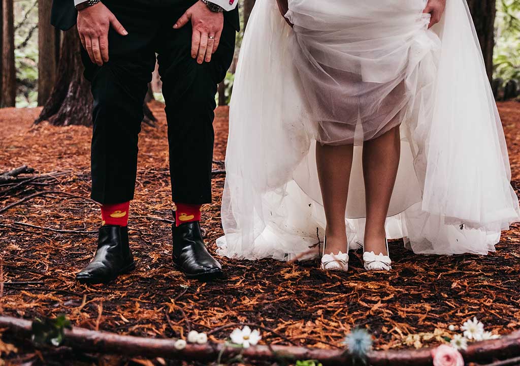 A bride and groom raise their trousers and dress to show funky socks.