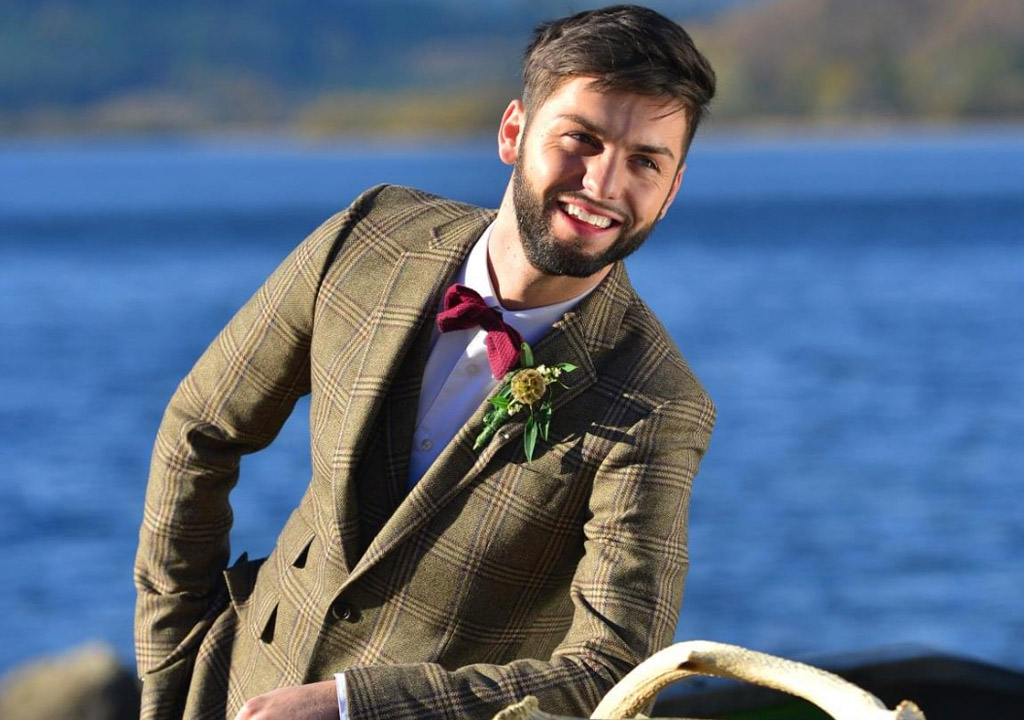 Sam the wedding planner leans casually by Loch Venachar.