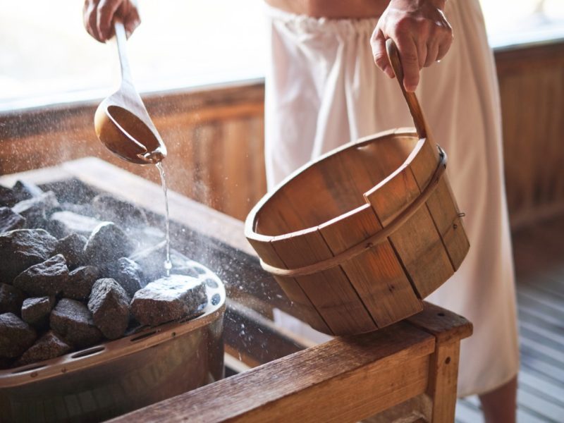 Man using a sauna adding water to the coals