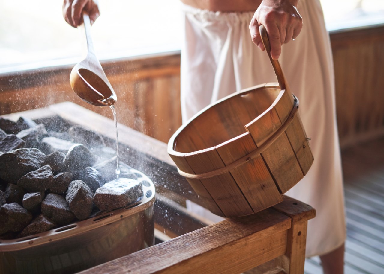 Man using a sauna adding water to the coals