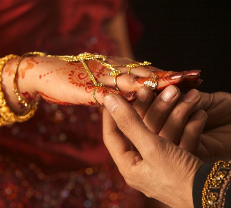 Photo of groom putting the ring on the finger at an Asian wedding