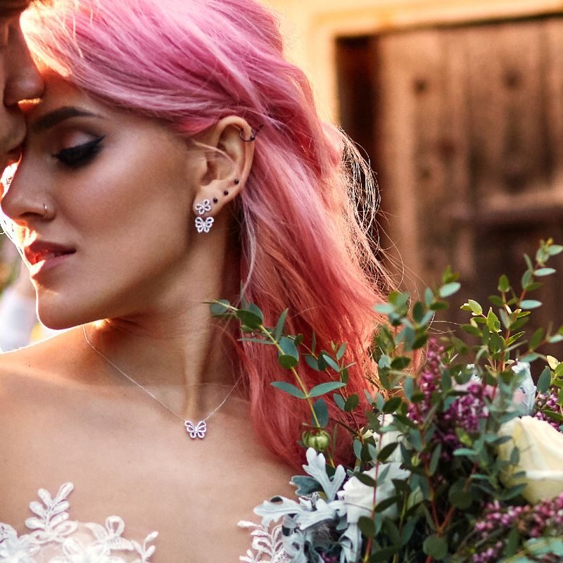 Stylish groom hugs from behind beautiful bride with pink hair