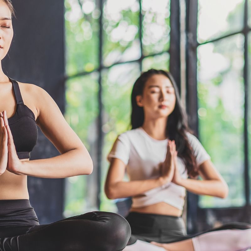 People seated cross-legged on mats in row do meditation practice