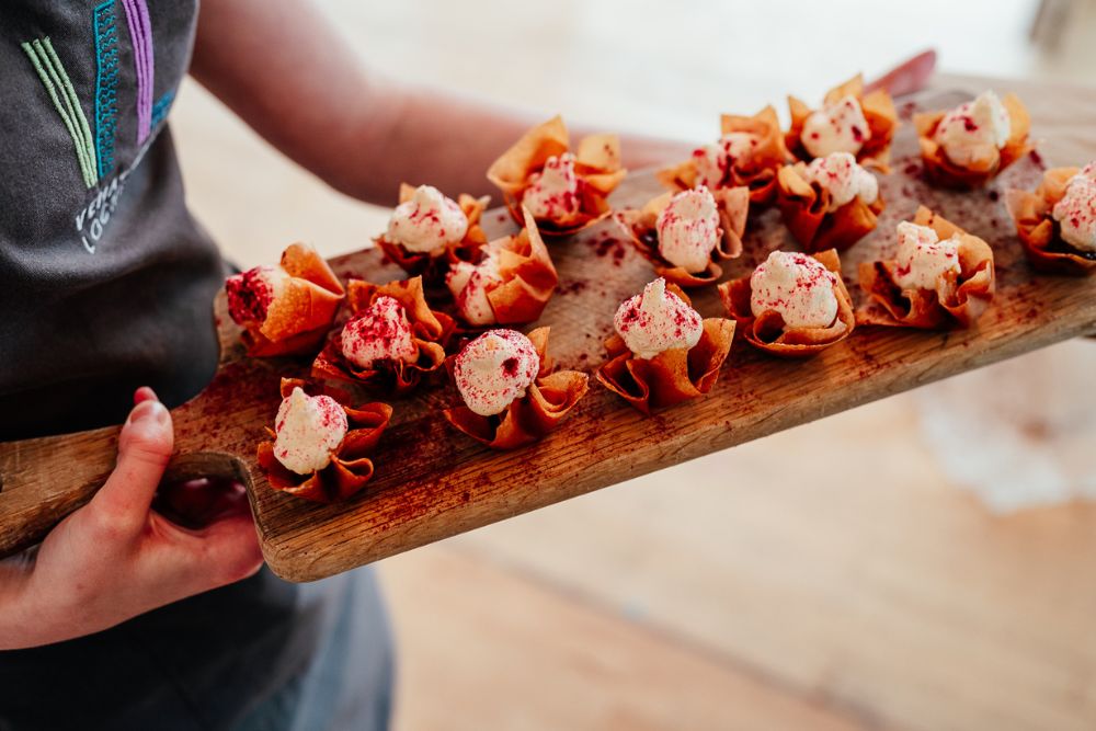 Canapes on a wooden board being held by a server.